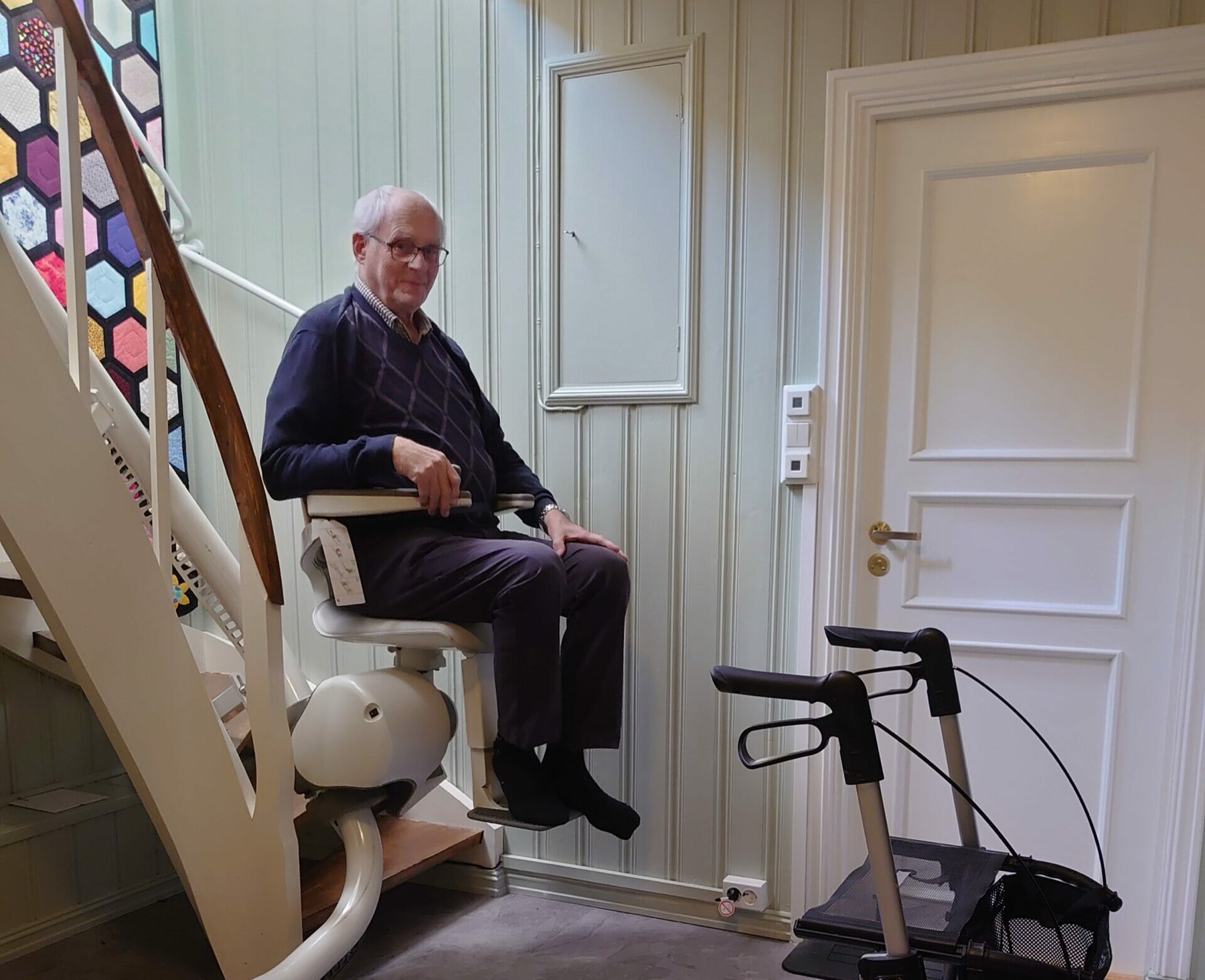 Eldre mann i trappeheis hjemme, med rullator ved siden av